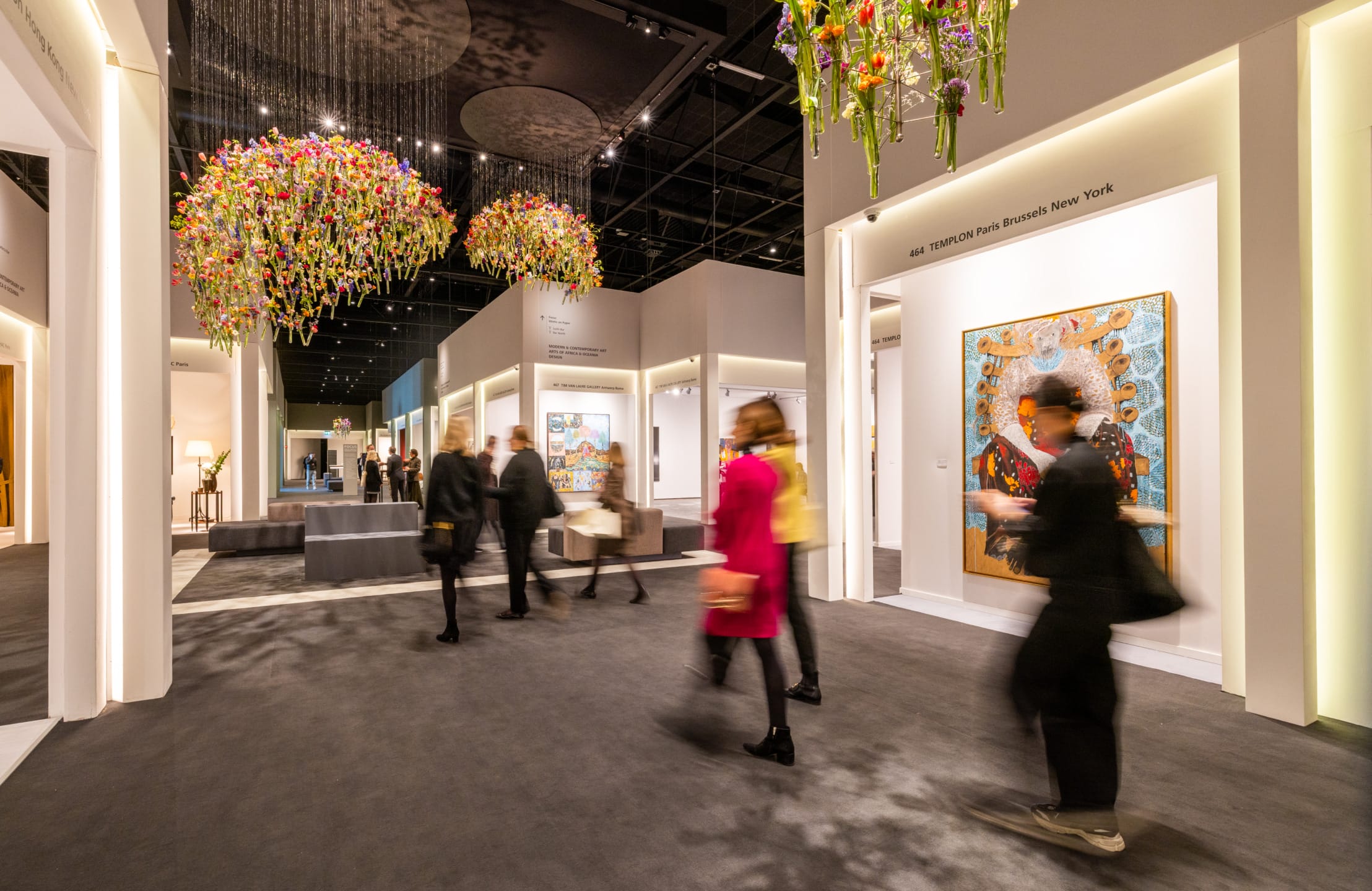 Visitors at TEFAF Maastricht beside a large-scale floral installation in the fair entrance hall.