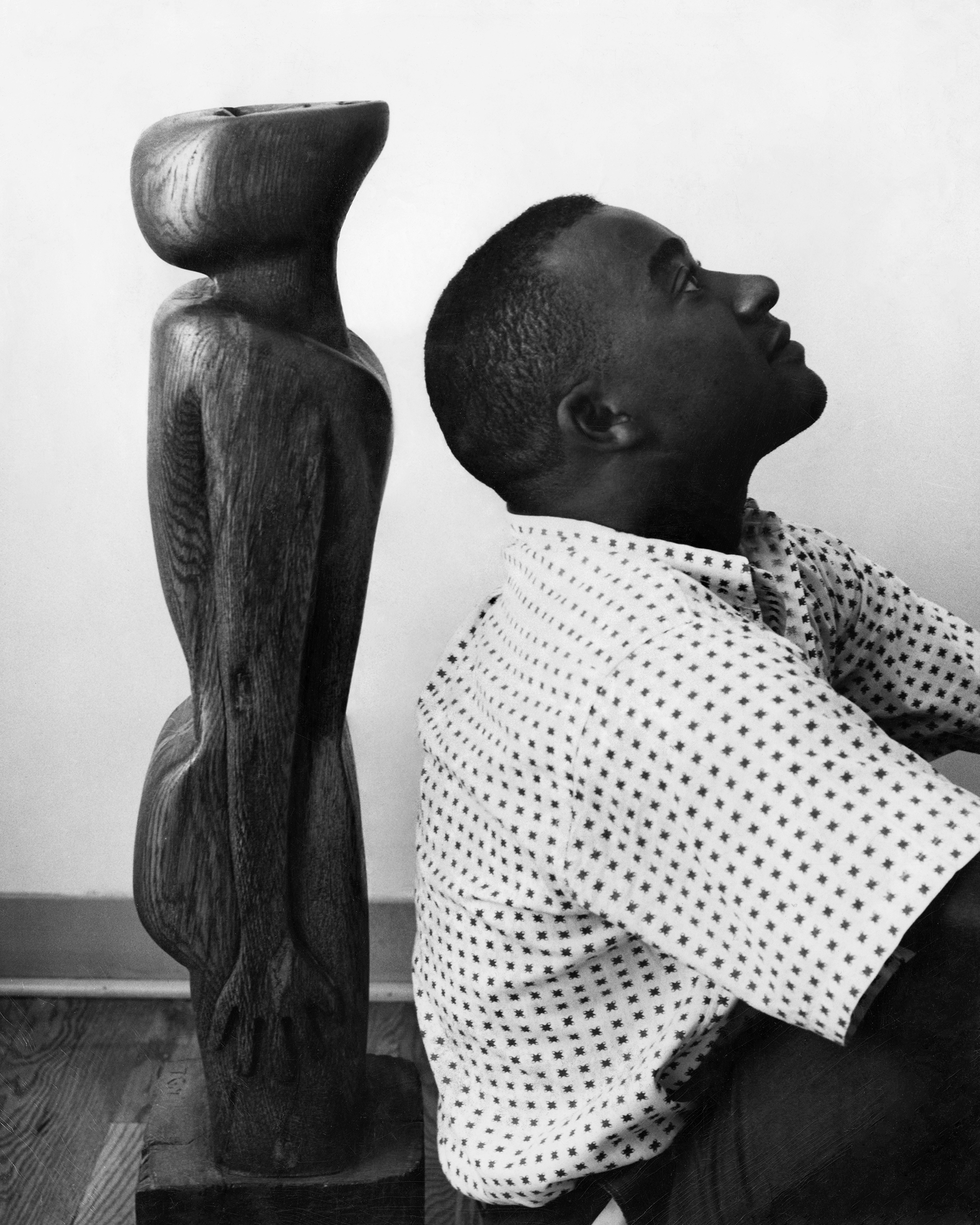 Thaddeus Mosley standing with one of his early wood sculptures in Pittsburgh